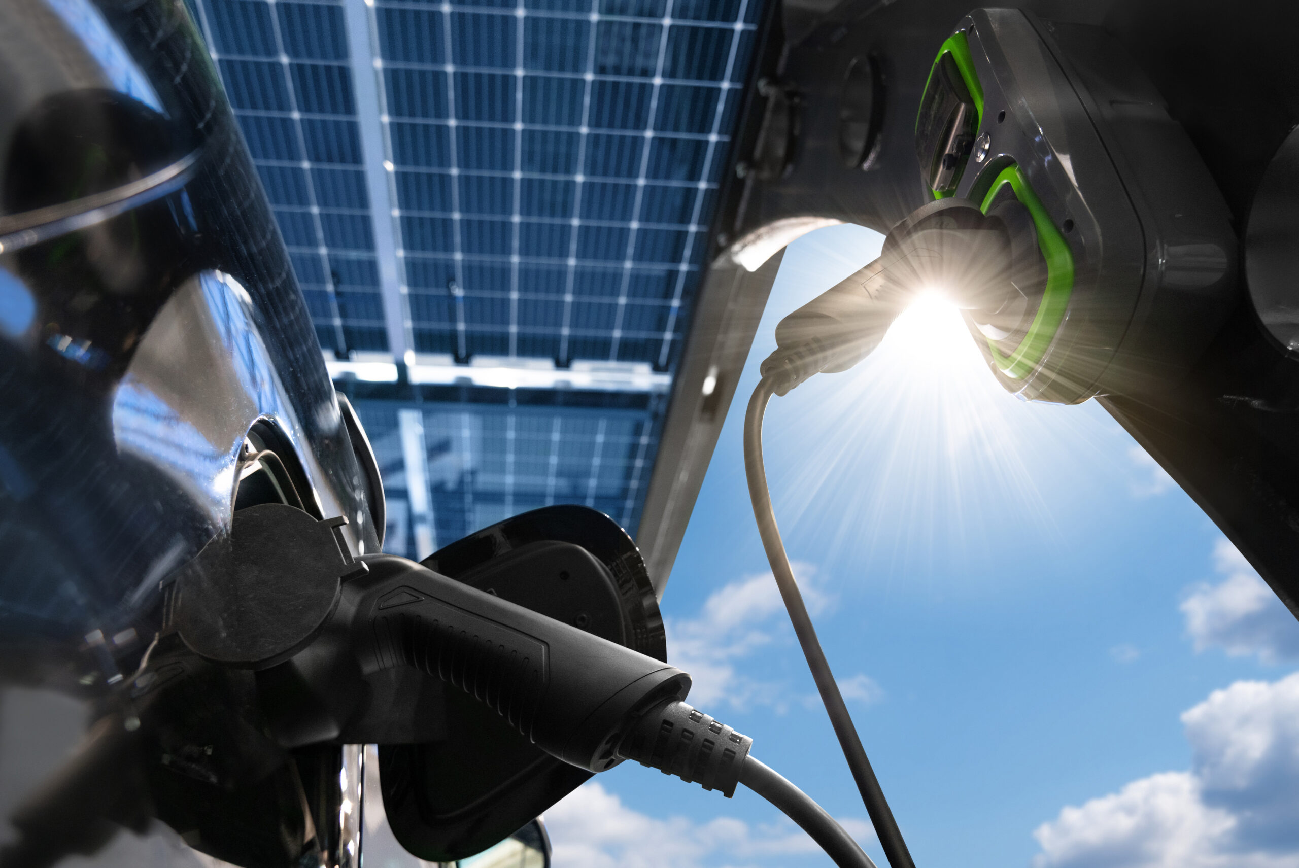 Electric car is charged from a charging station that takes energy from solar panels. Close up